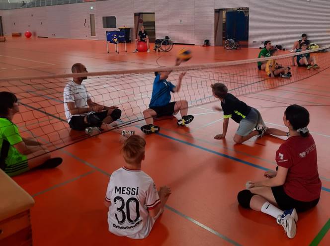 Kinder spielen im Sitzen Volleybal