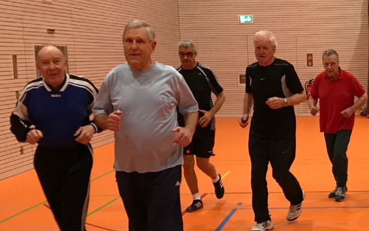 mehrere Männer laufen in lockerem Trab in der Sporthalle