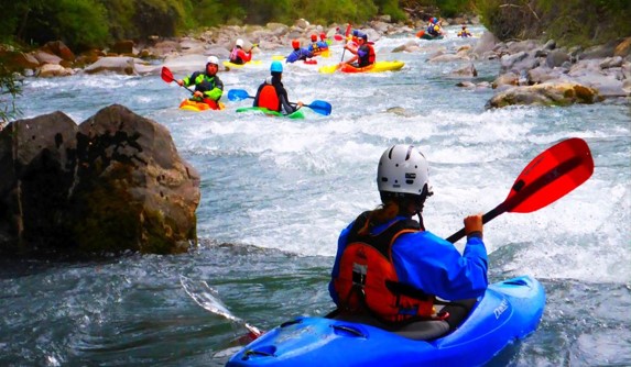  bunte Kajaks mit Paddlern im Wildwasser